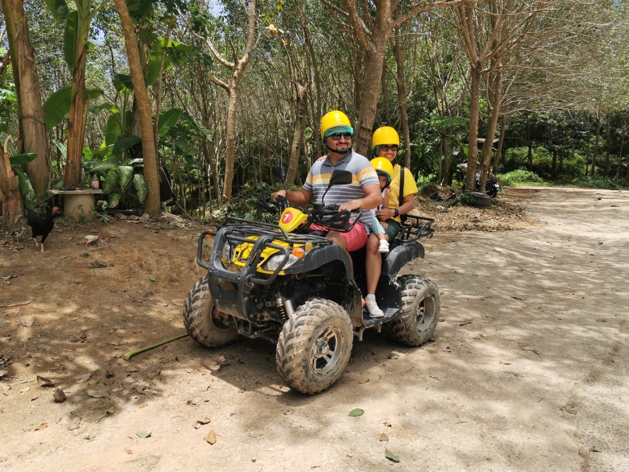 Family riding 3-up on a yellow ATV
