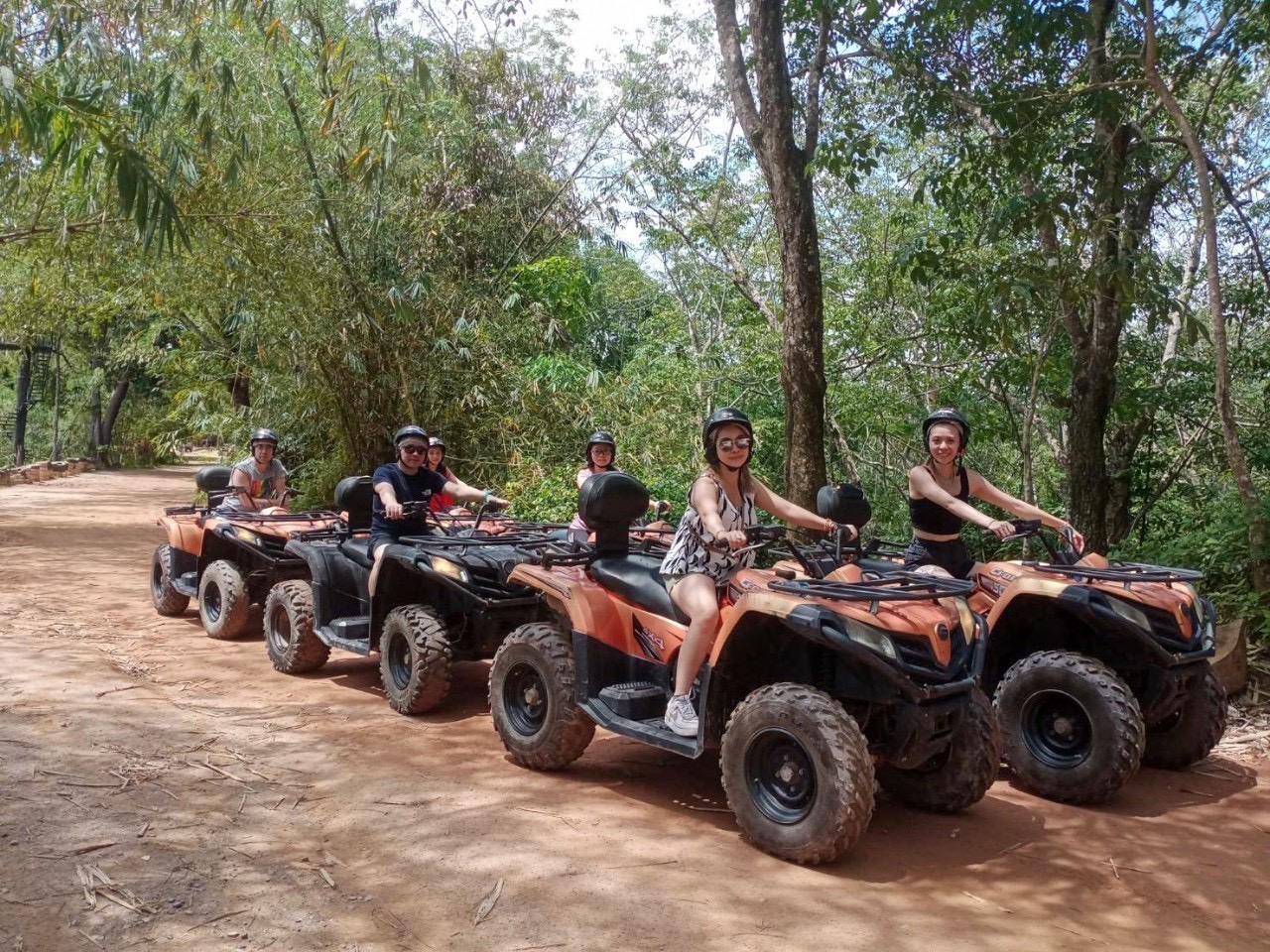 Group of women on orange ATVs on a jungle trail