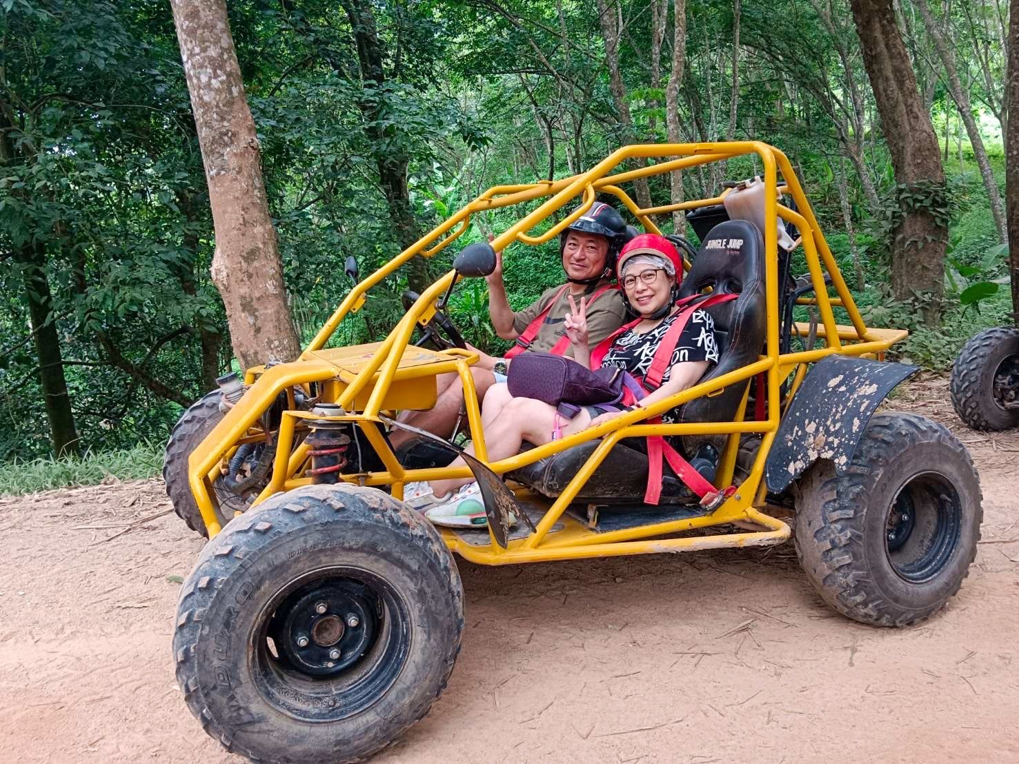 Couple in a yellow 2-seat buggy in the jungle